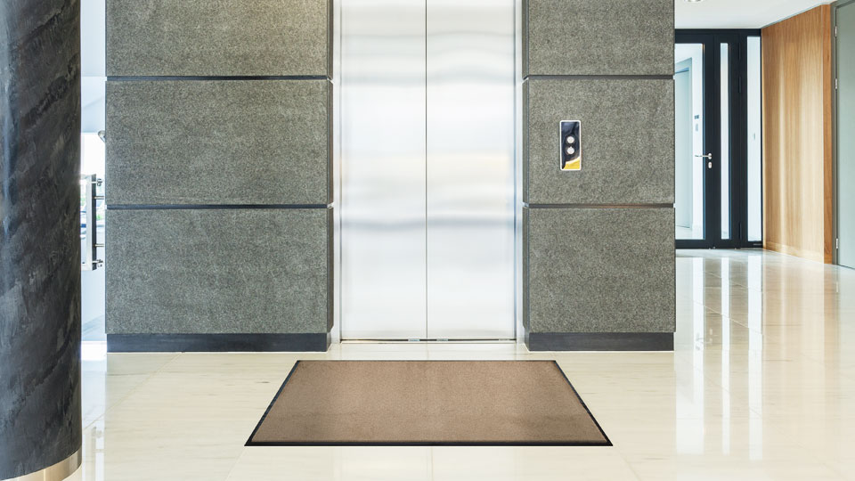 Taupenfarbige Schmutzfangmatte im Fahrstuhlvorraum